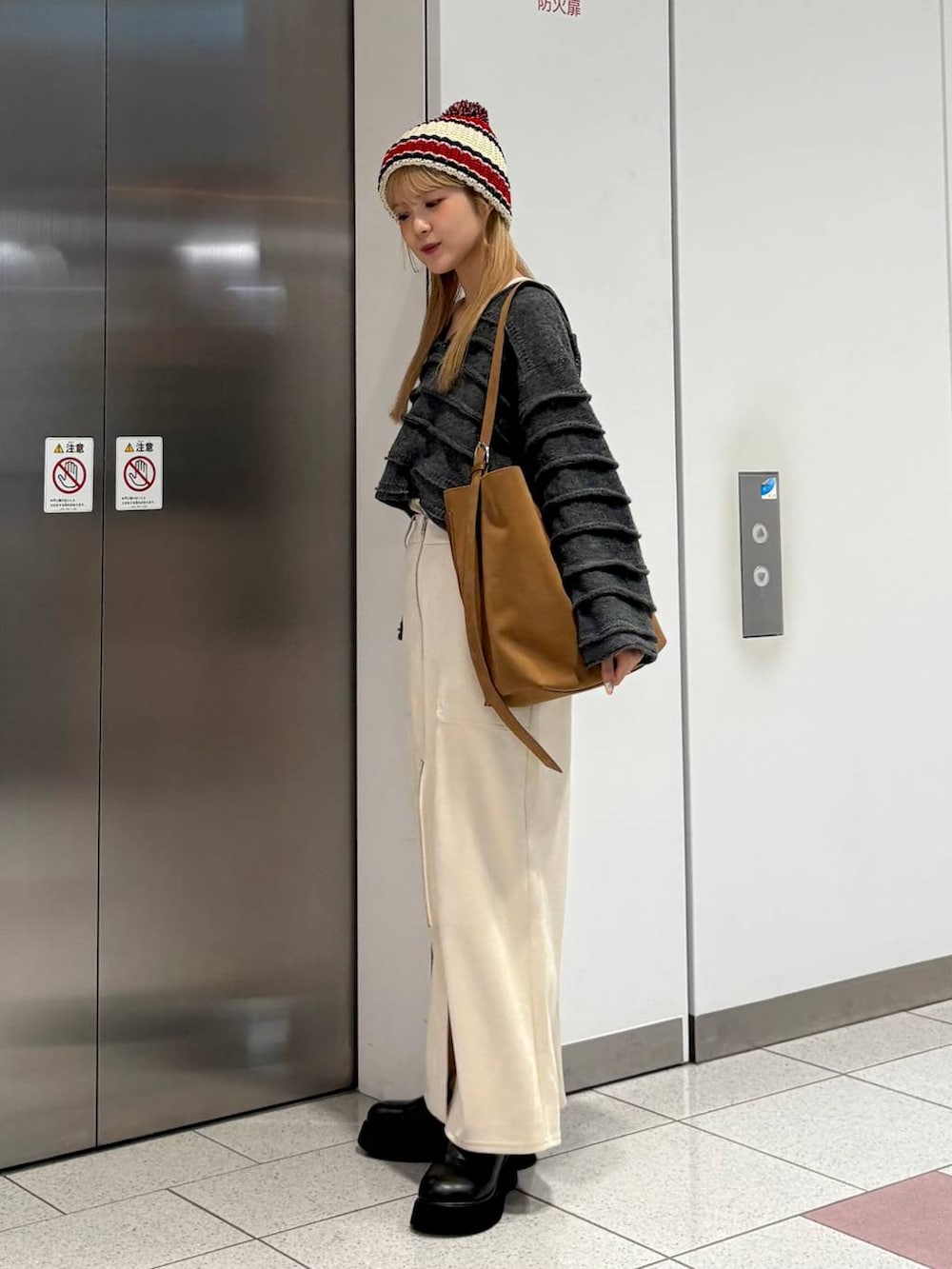 ホワイト系のスカート、ブラック系のサンダル、ベージュ系のショルダーバッグを着用したレディースの秋コーディネートの3枚目の写真