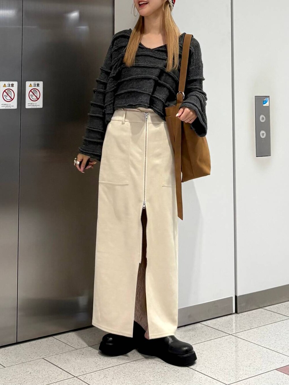 ホワイト系のスカート、ブラック系のサンダル、ベージュ系のショルダーバッグを着用したレディースの秋コーディネートの2枚目の写真