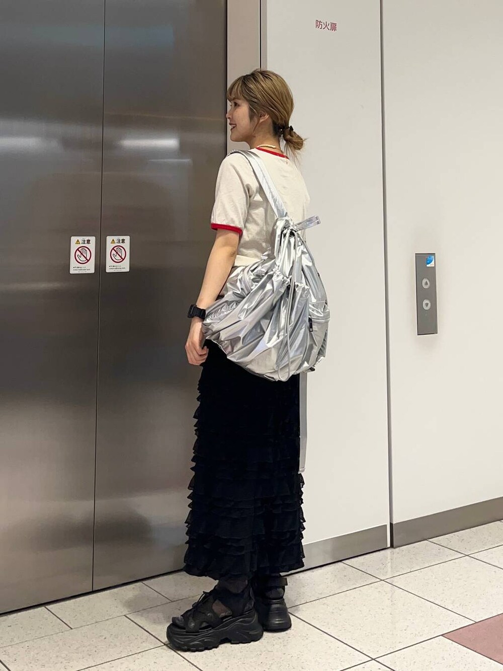 ブラック系のサンダル、ブラック系のスカート、シルバー系のバックパック/リュックを着用したレディースの春コーディネートの4枚目の写真