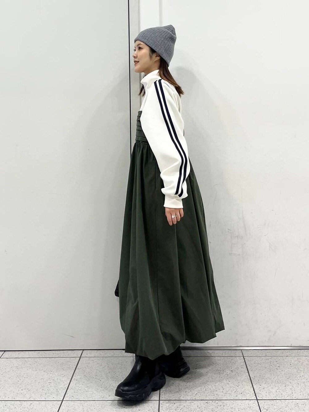 ブラック系のハンドバッグ、グリーン系のワンピース、ブラック系のブーツを着用したレディースの冬コーディネートの4枚目の写真