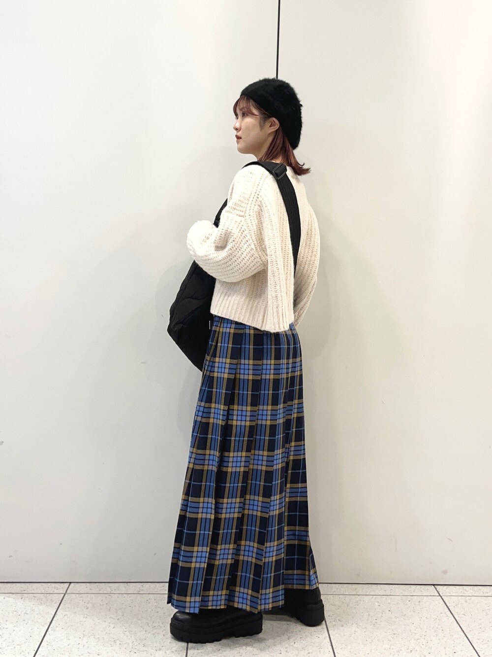 ブラック系のショルダーバッグ、ブルー系のスカート、ブラック系のブーツを着用したレディースの秋コーディネートの3枚目の写真