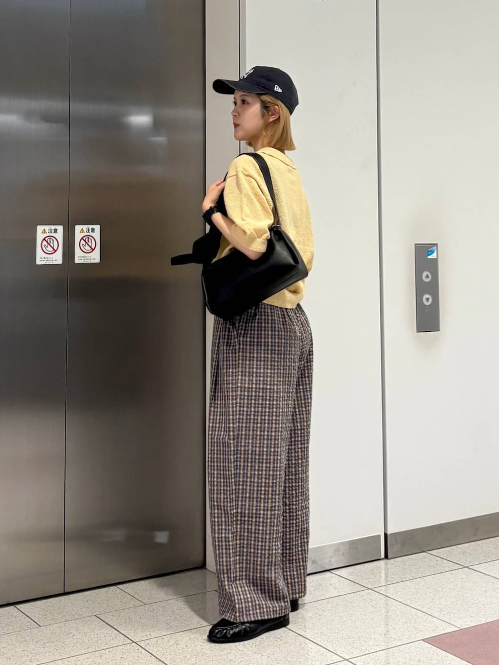 ブラック系のローファー、ブラック系のショルダーバッグ、ベージュ系のTシャツ/カットソーを着用したレディースの夏コーディネートの5枚目の写真