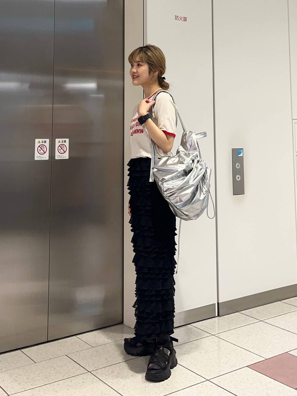 ブラック系のサンダル、ブラック系のスカート、シルバー系のバックパック/リュックを着用したレディースの春コーディネートの3枚目の写真