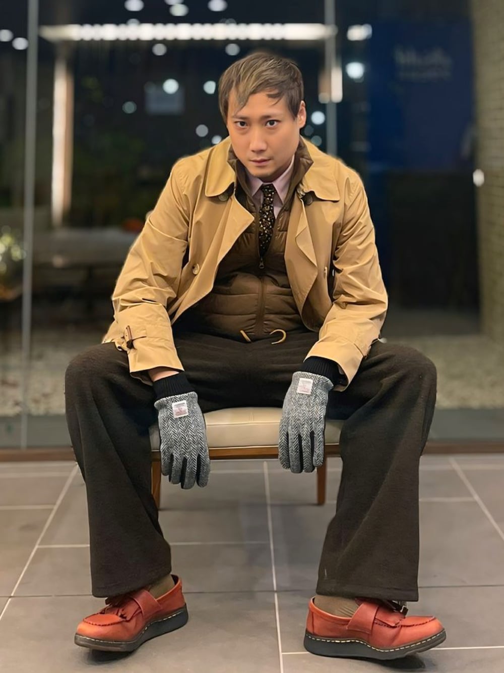 ベージュ系のトレンチコート、ブラウン系のスウェットパンツ、レッド系のローファーを着用したメンズの冬コーディネートの2枚目の写真