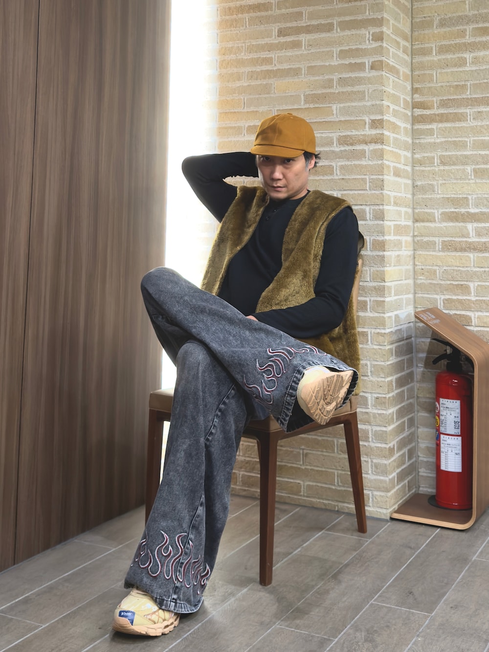 ブラック系のデニムパンツ、ブラック系のトップス、ブラウン系のベストを着用したメンズの冬コーディネートの2枚目の写真