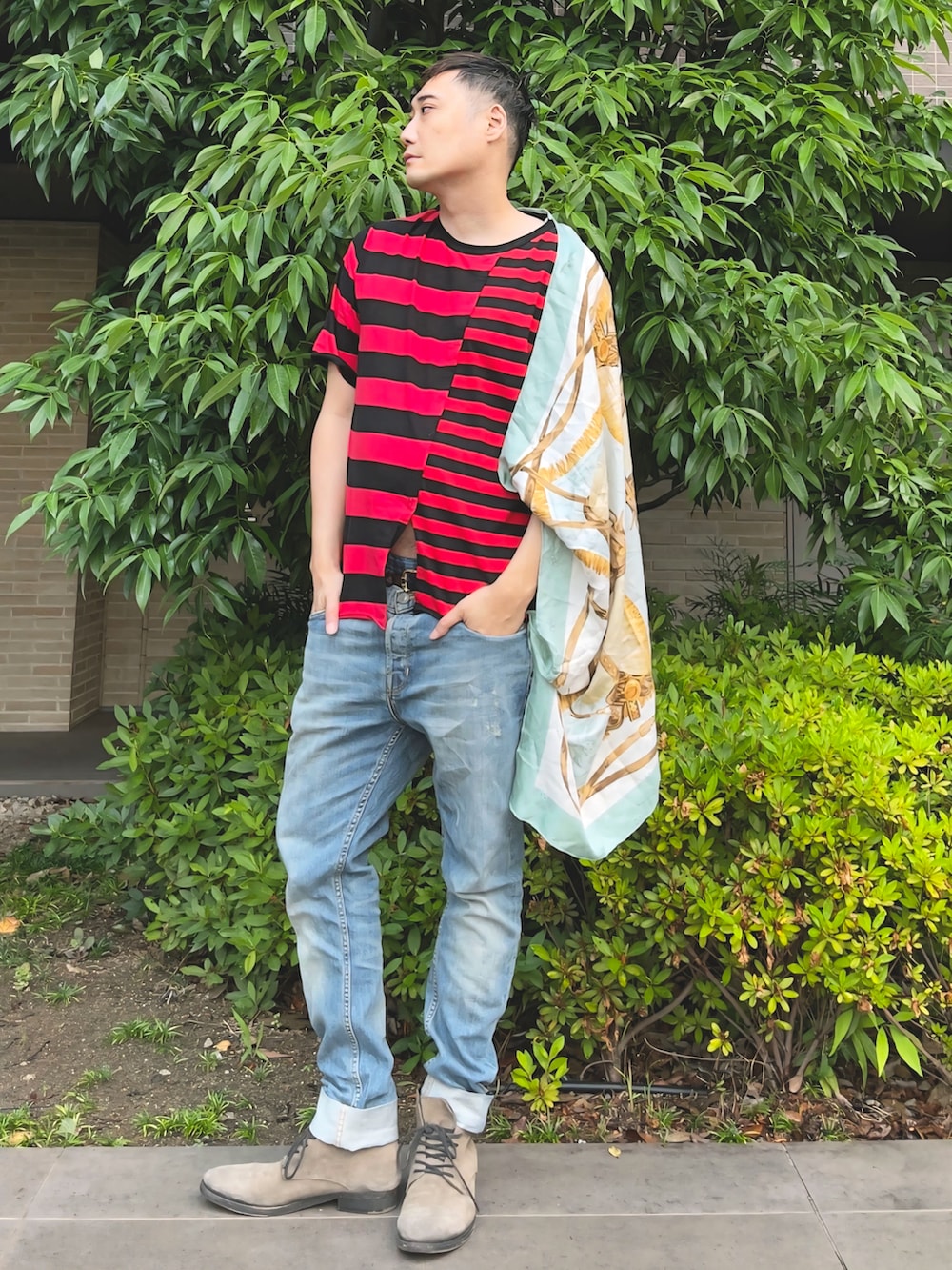 ブルー系のデニムパンツ、ベージュ系のブーツ、レッド系のTシャツ/カットソーを着用したメンズの夏コーディネートの3枚目の写真
