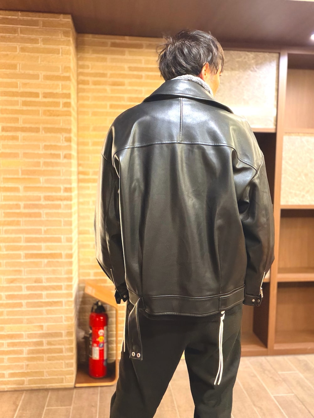 ブラック系のライダースジャケット、グレー系のパーカー、ブラック系のカーディガン/ボレロを着用したメンズの冬コーディネートの4枚目の写真