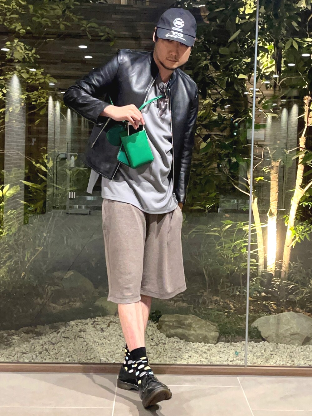 ブラック系のライダースジャケット、グリーン系のショルダーバッグ、ブラック系のその他シューズを着用したメンズの夏コーディネートの2枚目の写真
