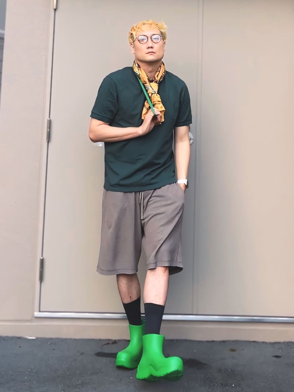 グリーン系のポロシャツ、グリーン系のレインシューズ、グリーン系のショルダーバッグを着用したメンズの夏コーディネートの3枚目の写真