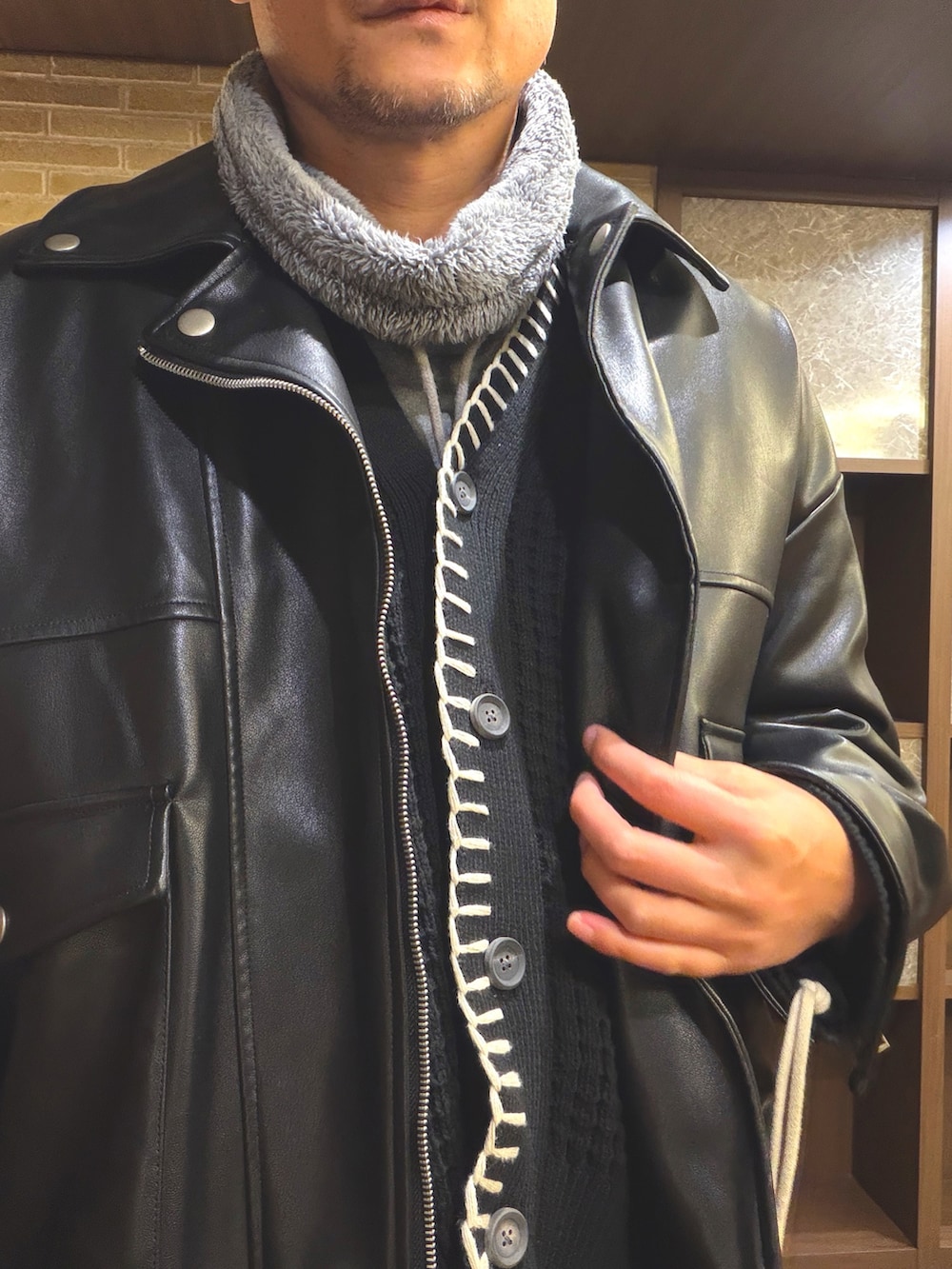 ブラック系のライダースジャケット、グレー系のパーカー、ブラック系のカーディガン/ボレロを着用したメンズの冬コーディネートの3枚目の写真