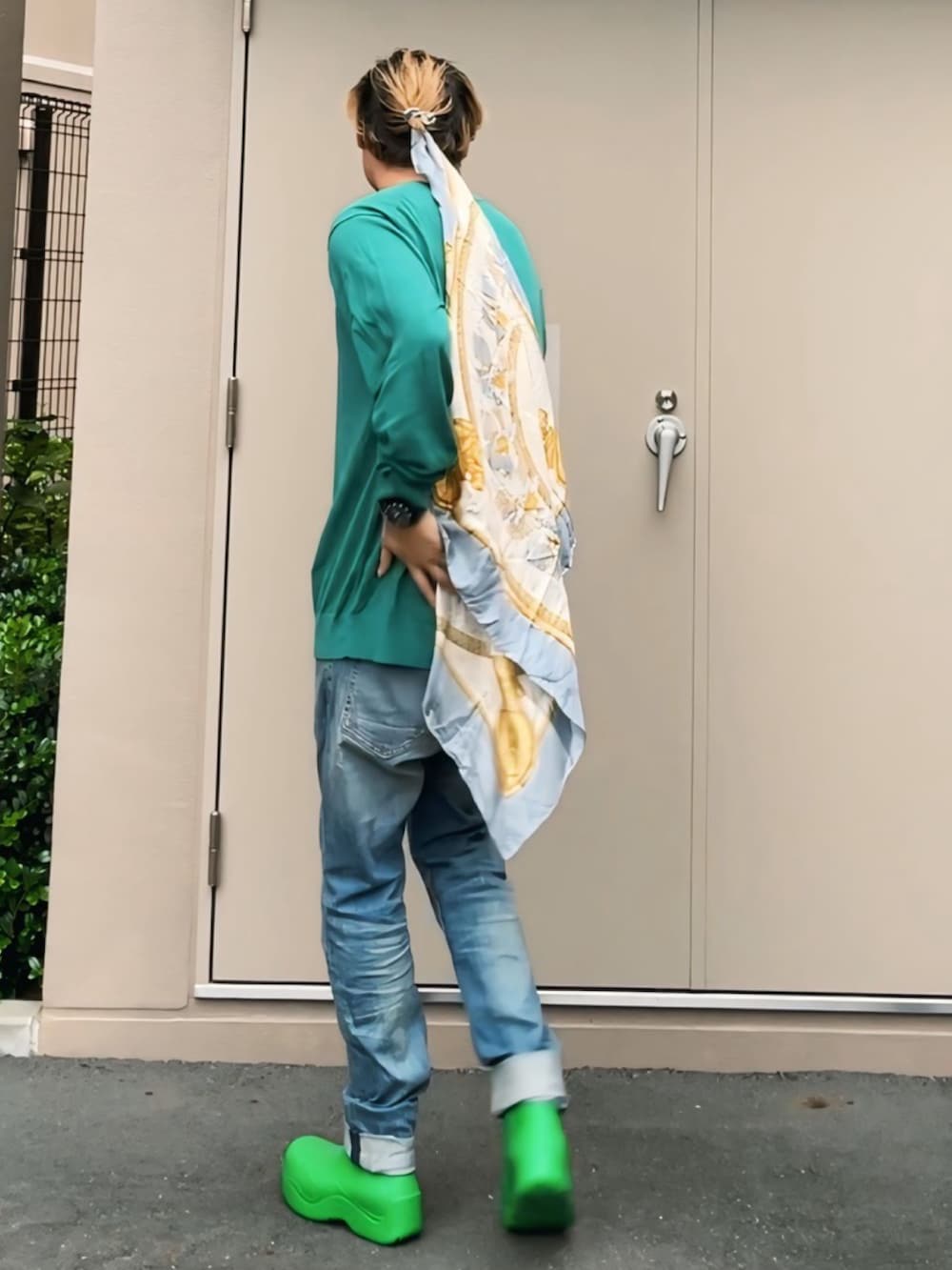 グリーン系のニット/セーター、ブルー系のデニムパンツ、グリーン系のレインシューズを着用したメンズの秋コーディネートの3枚目の写真