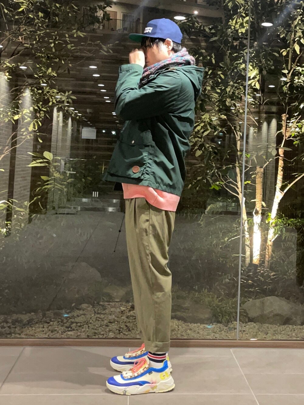 ピンク系のニット/セーター、グリーン系のマウンテンパーカー、グリーン系のその他パンツを着用したメンズの春コーディネートの4枚目の写真