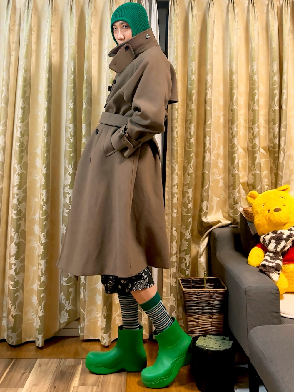 ベージュ系のトレンチコート、ブラック系のスラックス、グリーン系のレインシューズを着用したメンズの冬コーディネートの2枚目の写真