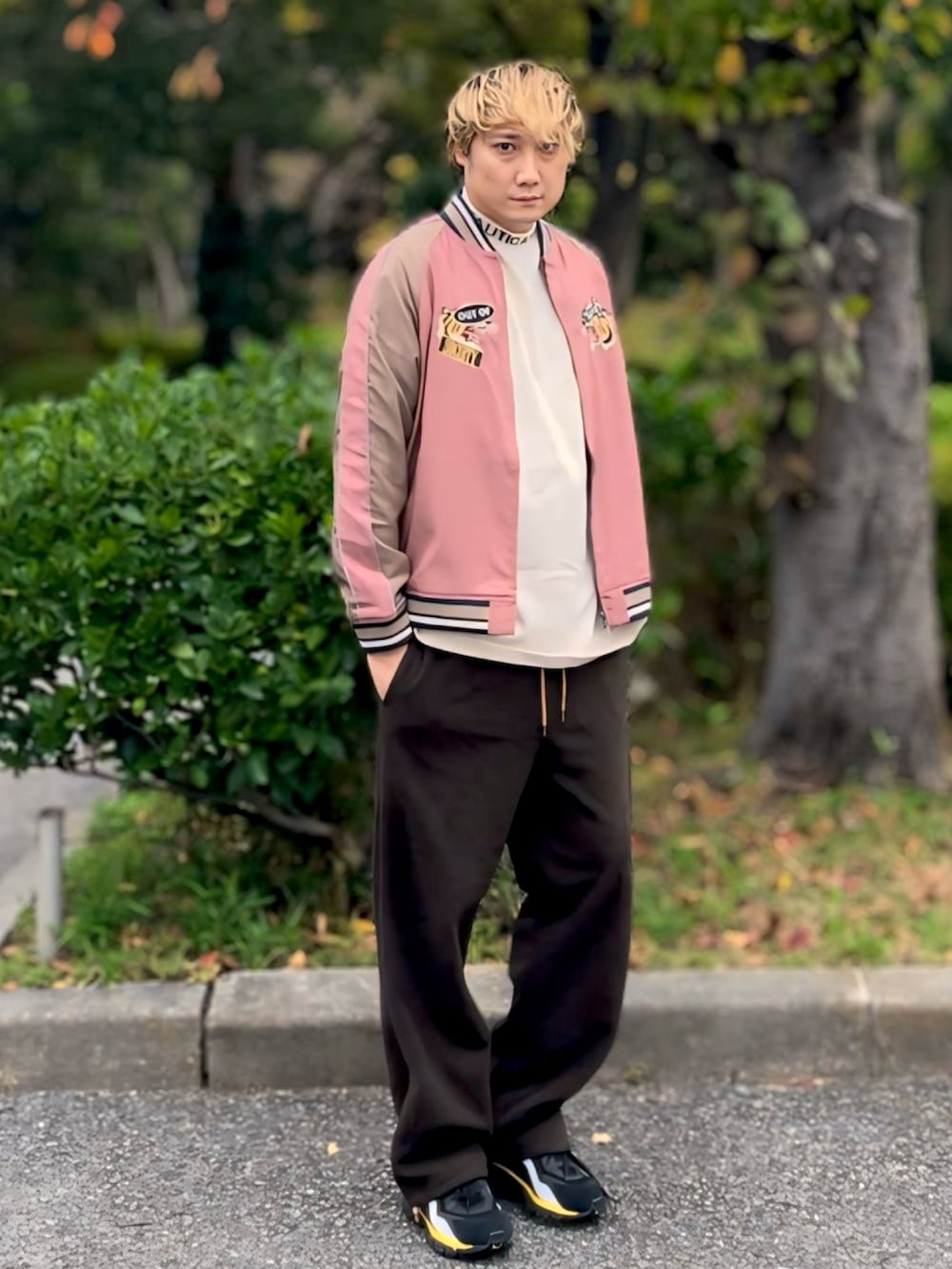 ピンク系のスカジャン、ベージュ系のTシャツ/カットソー、ブラウン系のスウェットパンツを着用したメンズの秋コーディネートの2枚目の写真