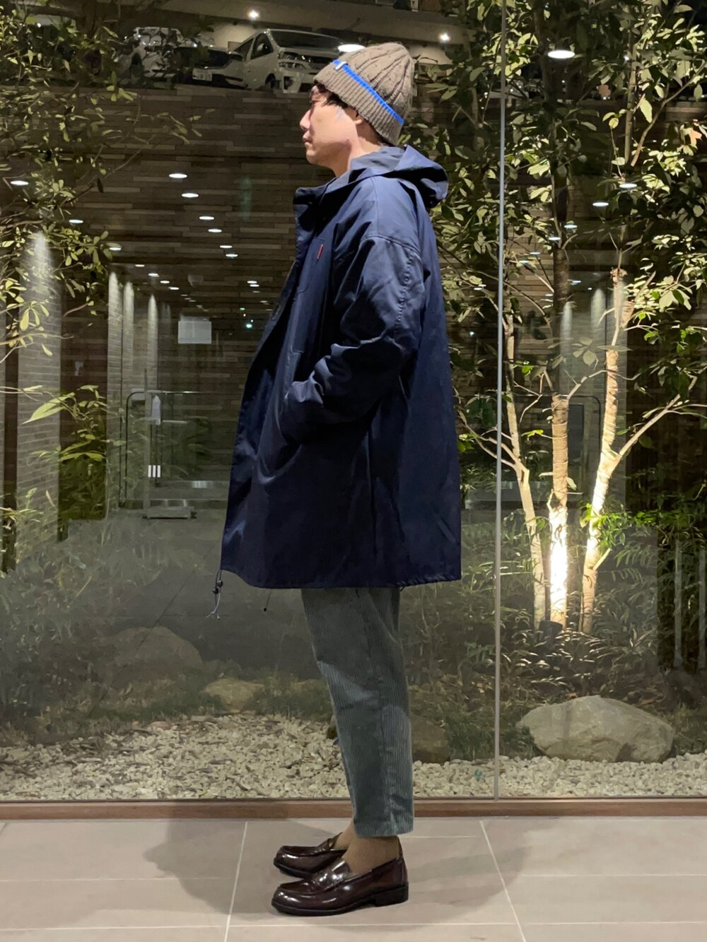 オレンジ系のTシャツ/カットソー、ブルー系のモッズコート、グリーン系のその他パンツを着用したメンズの春コーディネートの3枚目の写真