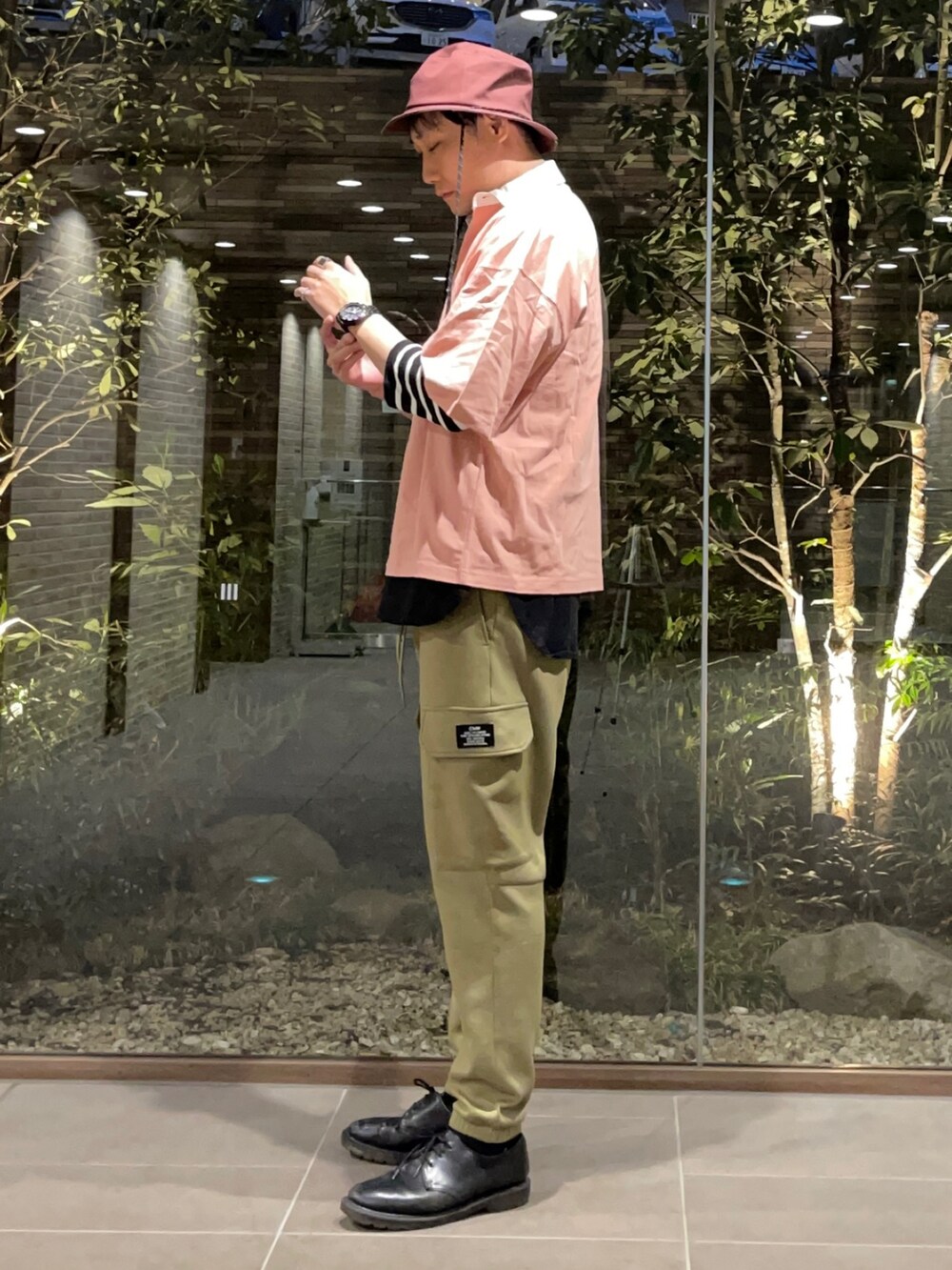 ピンク系のTシャツ/カットソー、ブラック系のTシャツ/カットソー、グリーン系のカーゴパンツを着用したメンズの春コーディネートの2枚目の写真