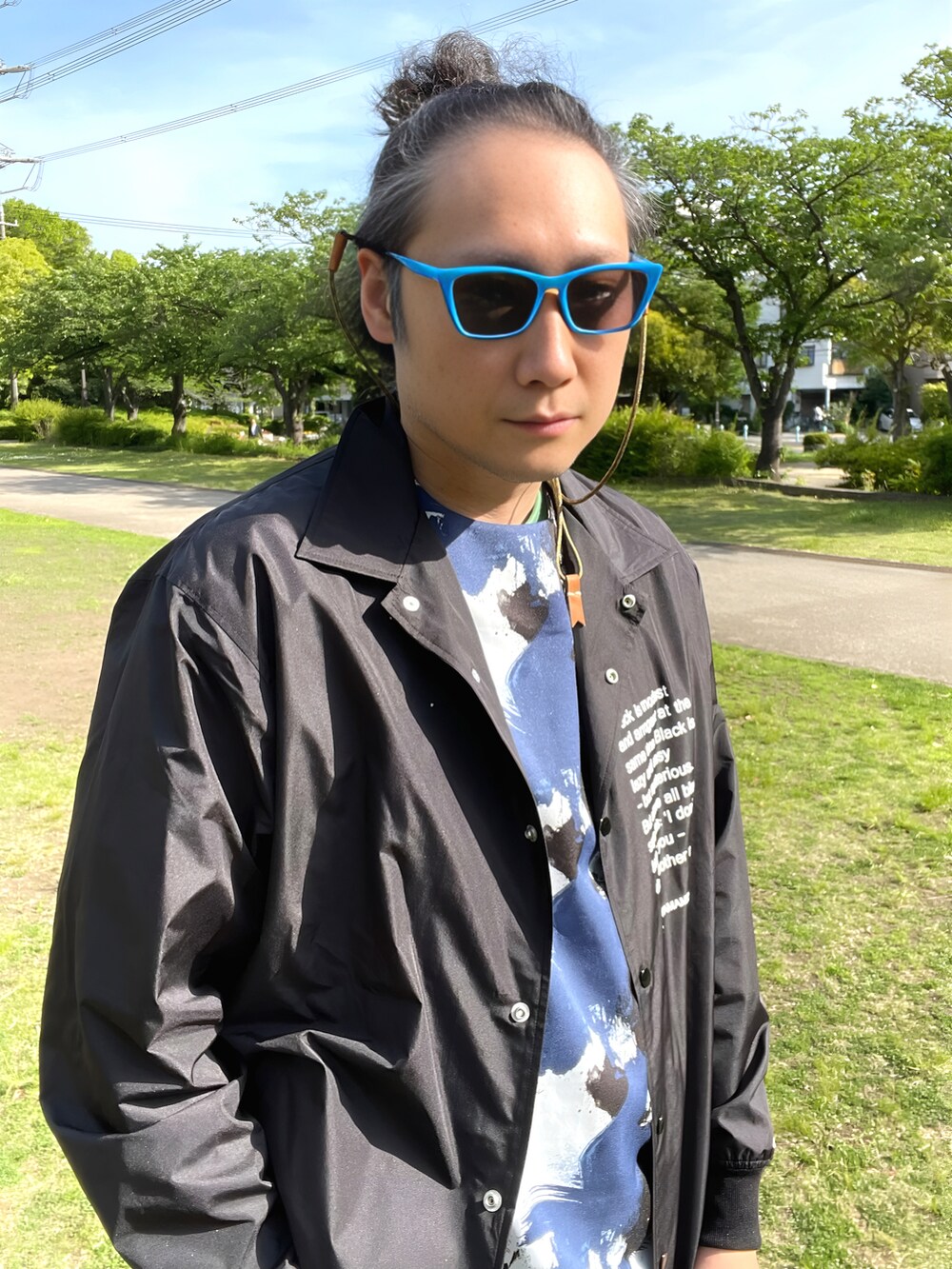 ブラック系のナイロンジャケット、ブルー系のTシャツ/カットソー、ブルー系のデニムパンツを着用したメンズの春コーディネートの3枚目の写真