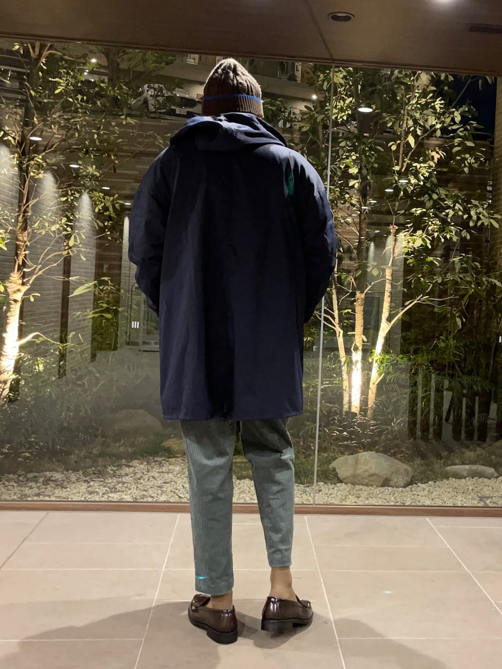 オレンジ系のTシャツ/カットソー、ブルー系のモッズコート、グリーン系のその他パンツを着用したメンズの春コーディネートの4枚目の写真