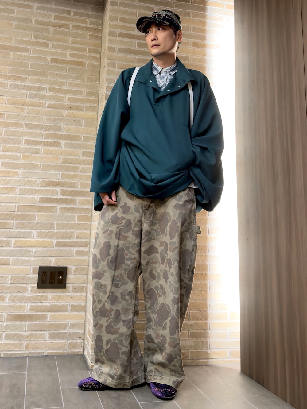 ブラウン系のその他パンツ、グリーン系のポンチョ、ブラック系のトートバッグを着用したメンズの春コーディネートの3枚目の写真