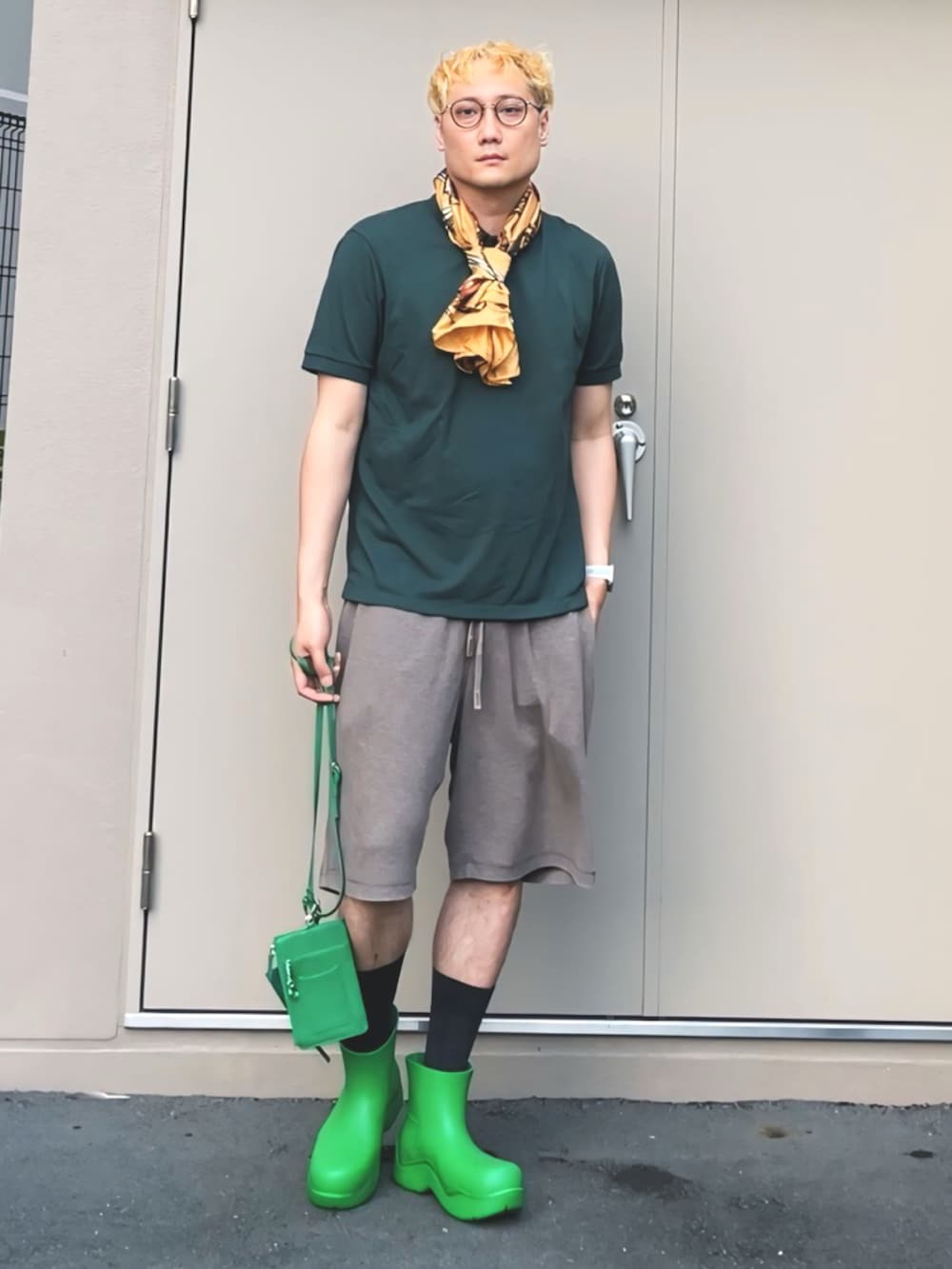 グリーン系のポロシャツ、グリーン系のレインシューズ、グリーン系のショルダーバッグを着用したメンズの夏コーディネートの2枚目の写真