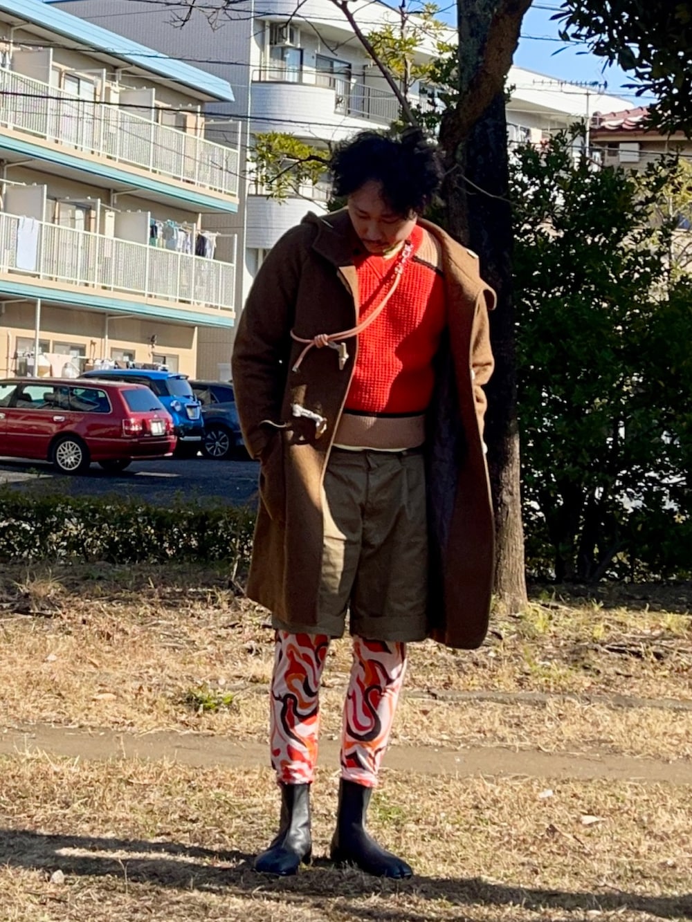 レッド系のニット/セーター、グリーン系のダッフルコート、ベージュ系のパンツを着用したメンズの冬コーディネートの2枚目の写真