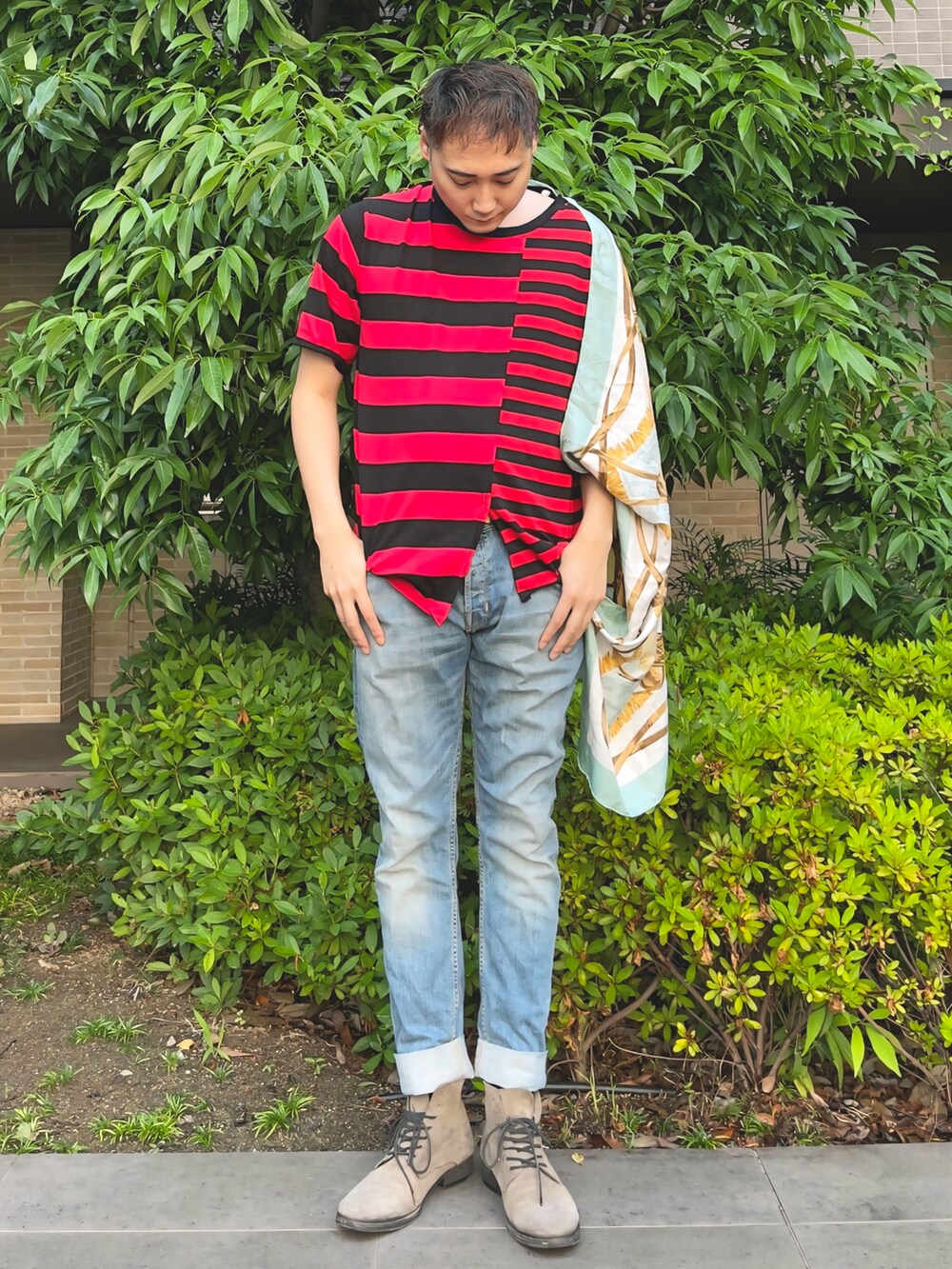 ブルー系のデニムパンツ、ベージュ系のブーツ、レッド系のTシャツ/カットソーを着用したメンズの夏コーディネートの2枚目の写真