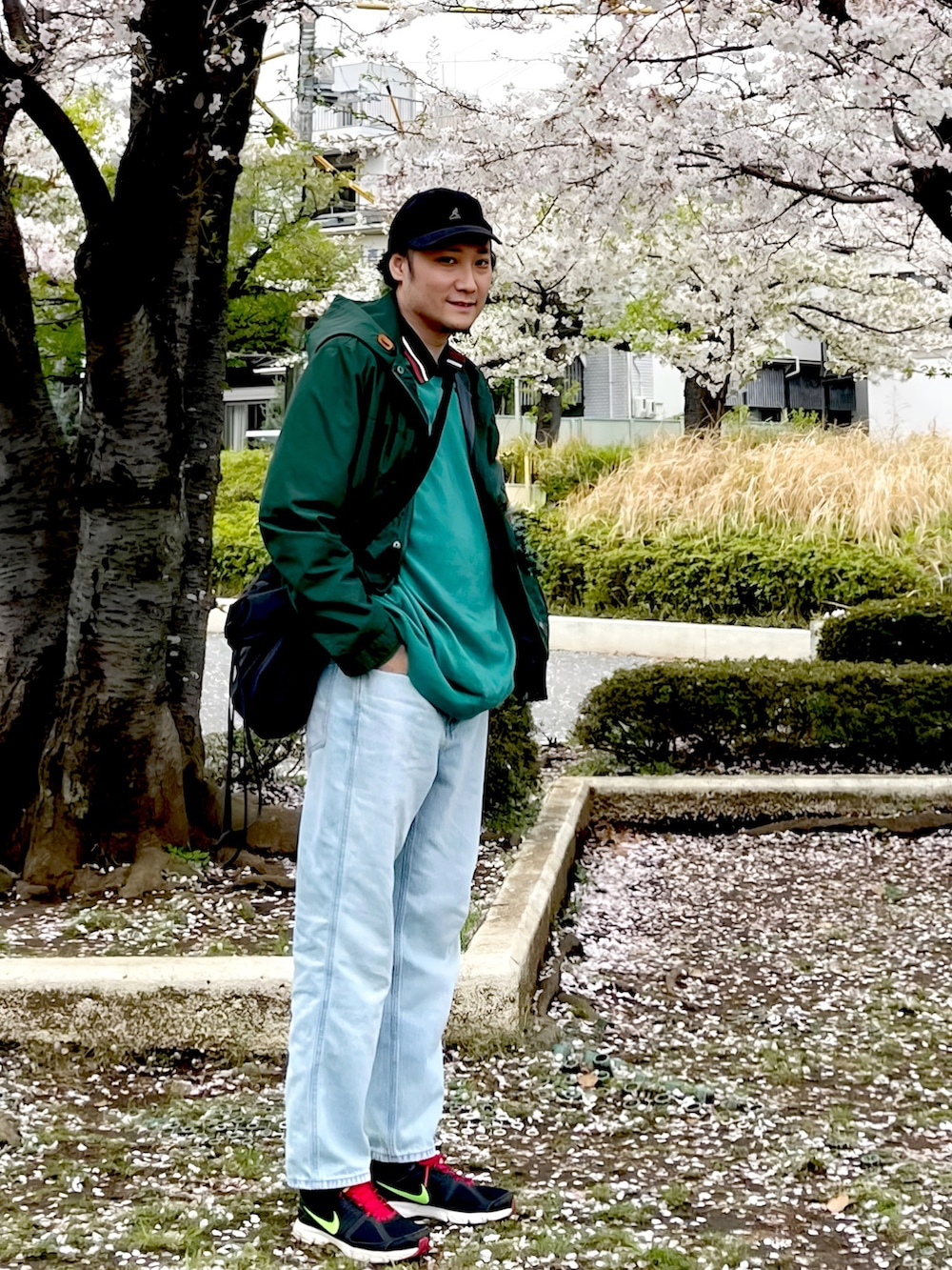 グリーン系のマウンテンパーカー、グリーン系のニット/セーター、ブラック系のショルダーバッグを着用したメンズの春コーディネートの2枚目の写真