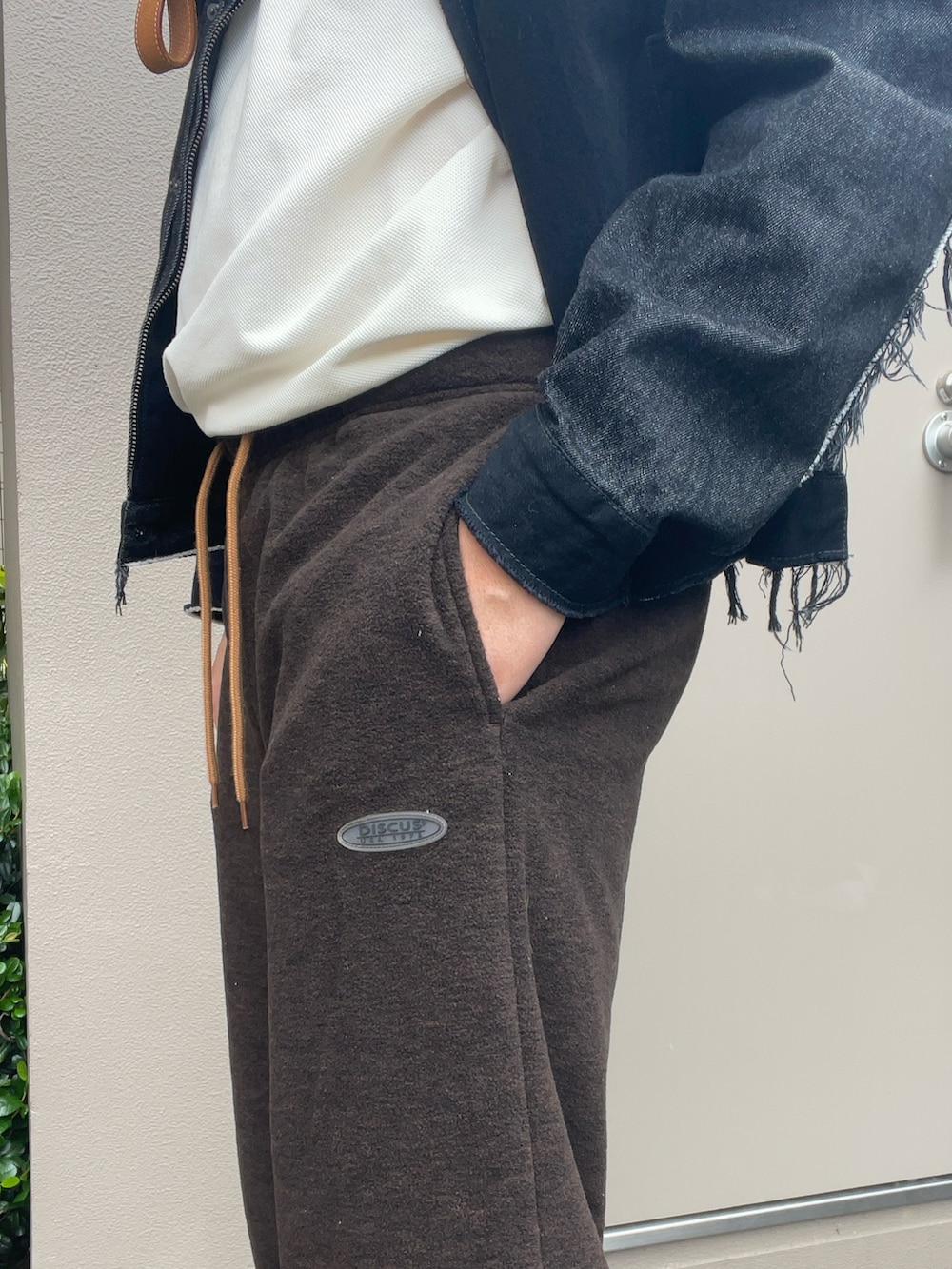 ブラック系のデニムジャケット、ブラウン系のスウェットパンツ、オレンジ系のスニーカーを着用したメンズの秋コーディネートの2枚目の写真