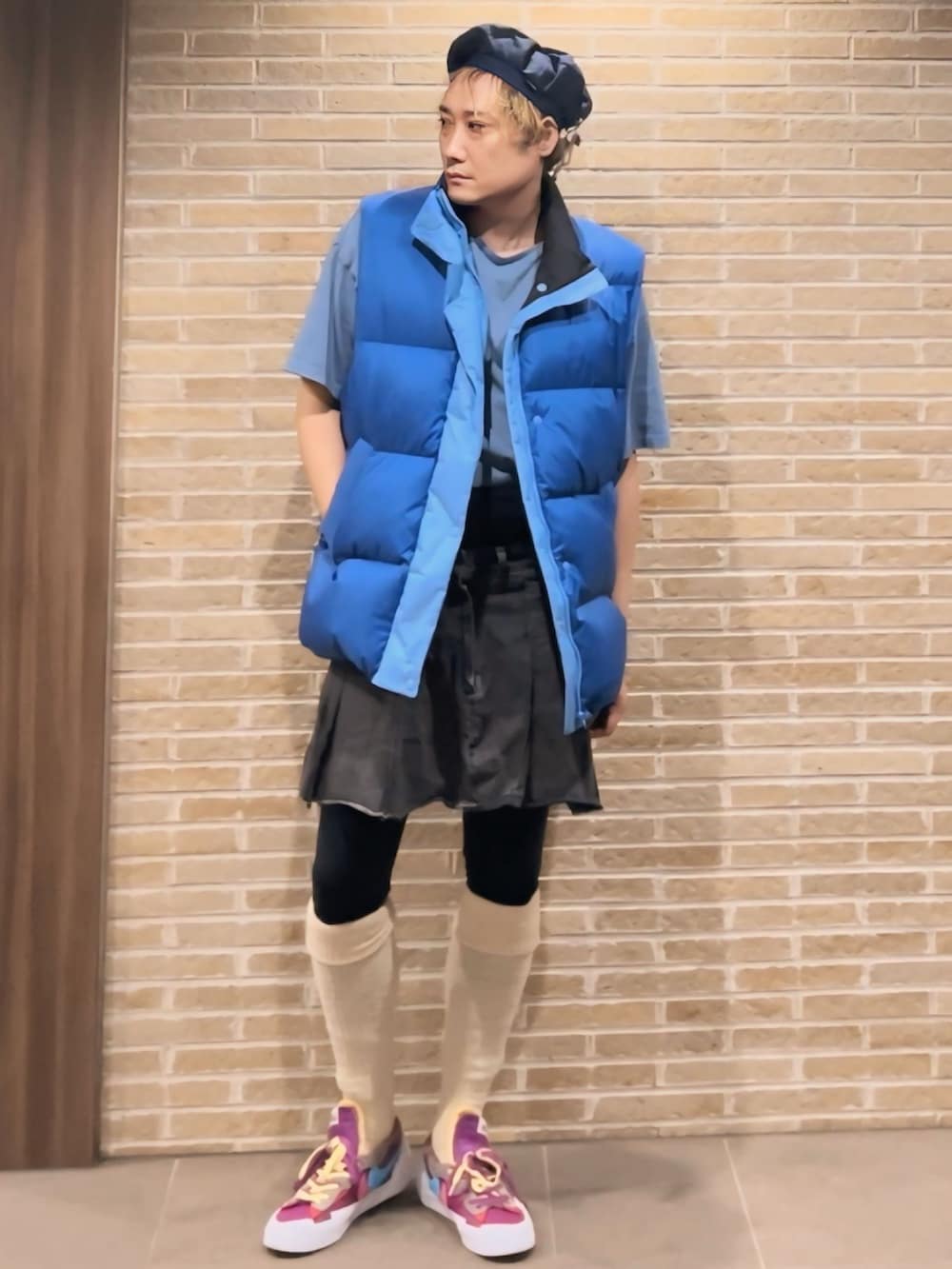 ブルー系のダウンベスト、グレー系のデニムスカート、パープル系のスニーカーを着用したメンズの秋コーディネートの3枚目の写真