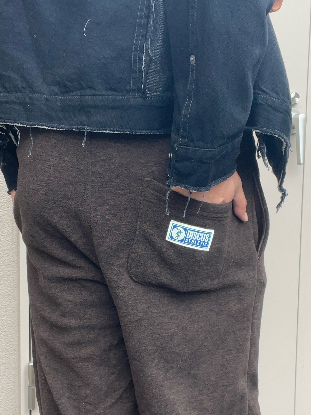 ブラック系のデニムジャケット、ブラウン系のスウェットパンツ、オレンジ系のスニーカーを着用したメンズの秋コーディネートの3枚目の写真