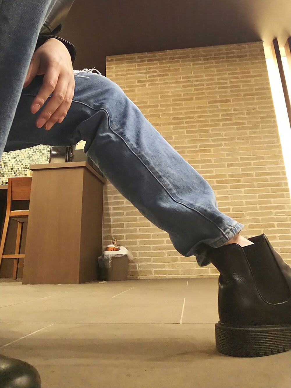 ブラック系のライダースジャケット、ブルー系のデニムパンツ、オレンジ系のニット/セーターを着用したメンズの冬コーディネートの5枚目の写真