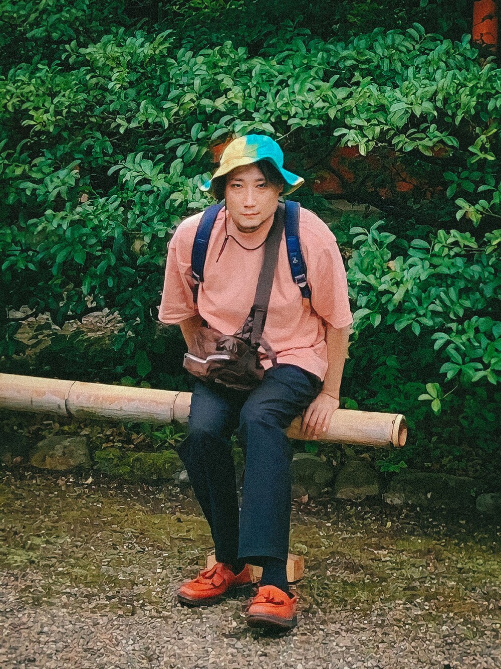 ピンク系のTシャツ/カットソー、ブルー系のバックパック/リュック、ブラック系のスラックスを着用したメンズの夏コーディネートの5枚目の写真