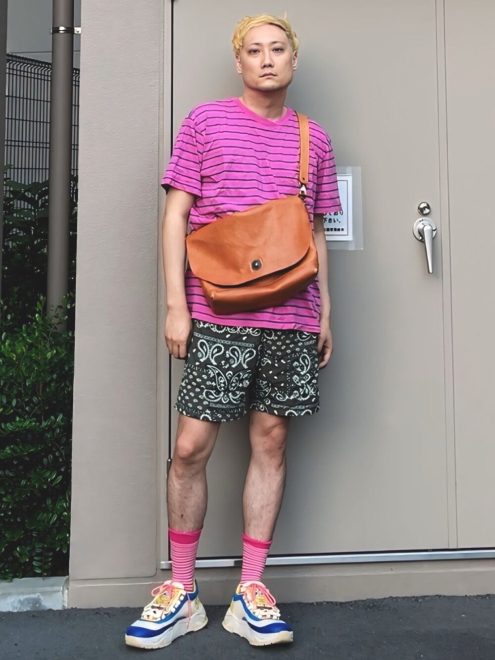 ピンク系のTシャツ/カットソー、ブラウン系のショルダーバッグ、グリーン系のパンツを着用したメンズの夏コーディネートの2枚目の写真