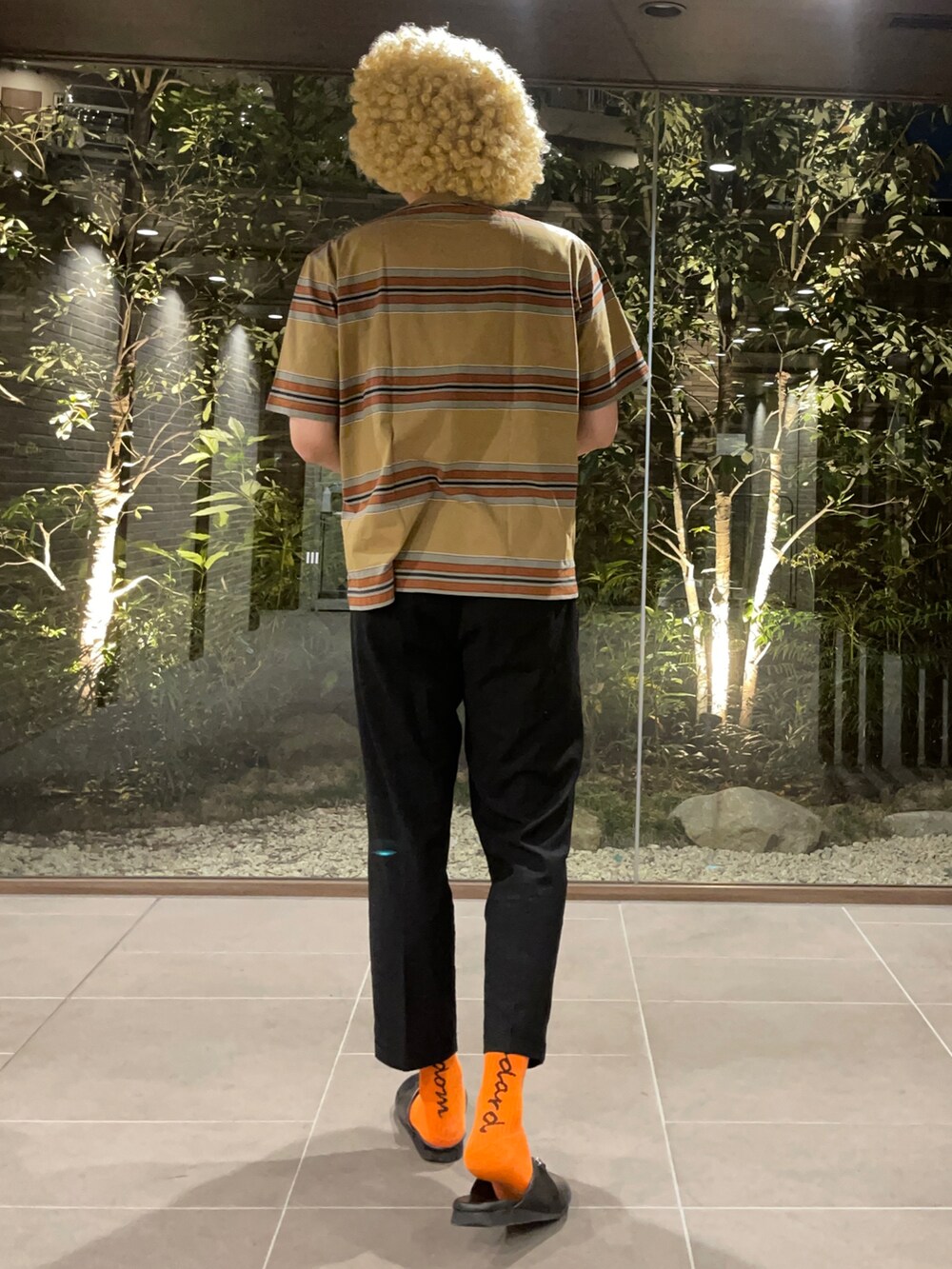 ブラウン系のTシャツ/カットソー、ブラック系のスラックス、ブラック系のサンダルを着用したメンズの春コーディネートの3枚目の写真