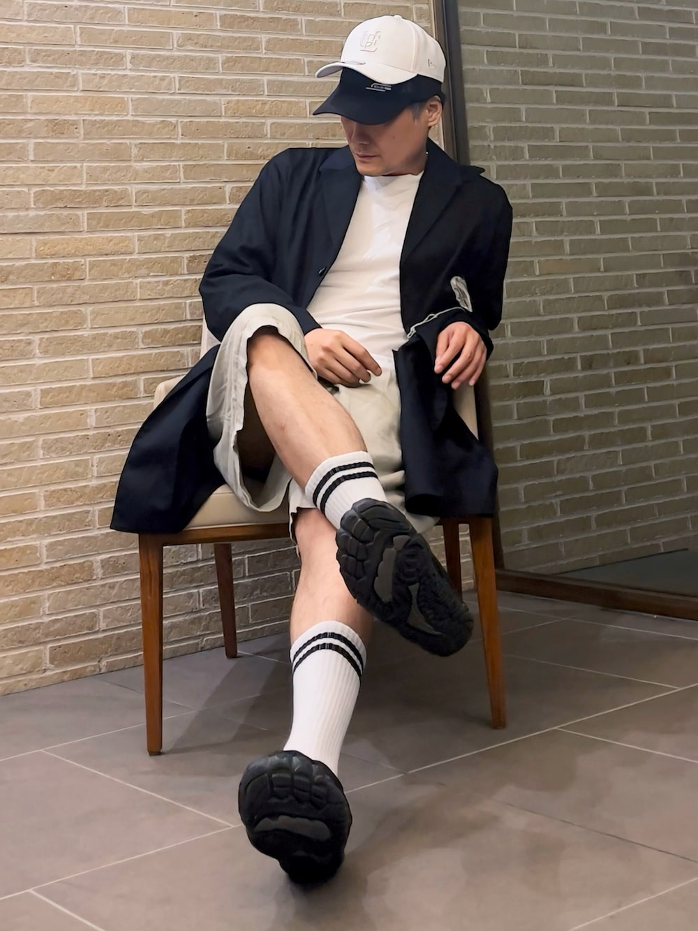 ホワイト系のTシャツ/カットソー、ブラック系のジャケット/アウター、ベージュ系のチノパンツを着用したメンズの秋コーディネートの3枚目の写真