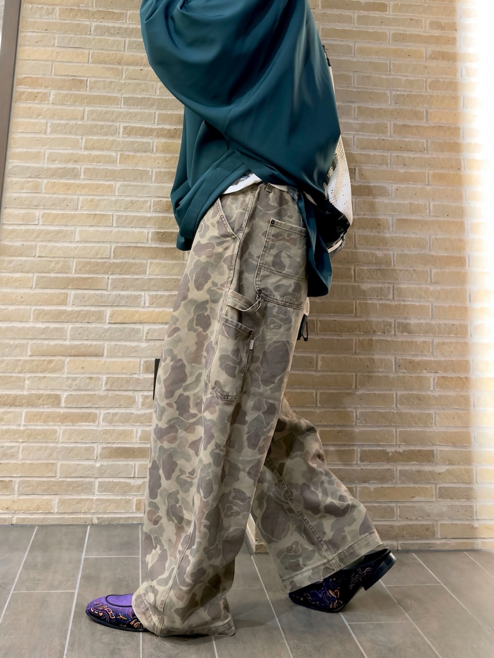 ブラウン系のその他パンツ、グリーン系のポンチョ、ブラック系のトートバッグを着用したメンズの春コーディネートの4枚目の写真