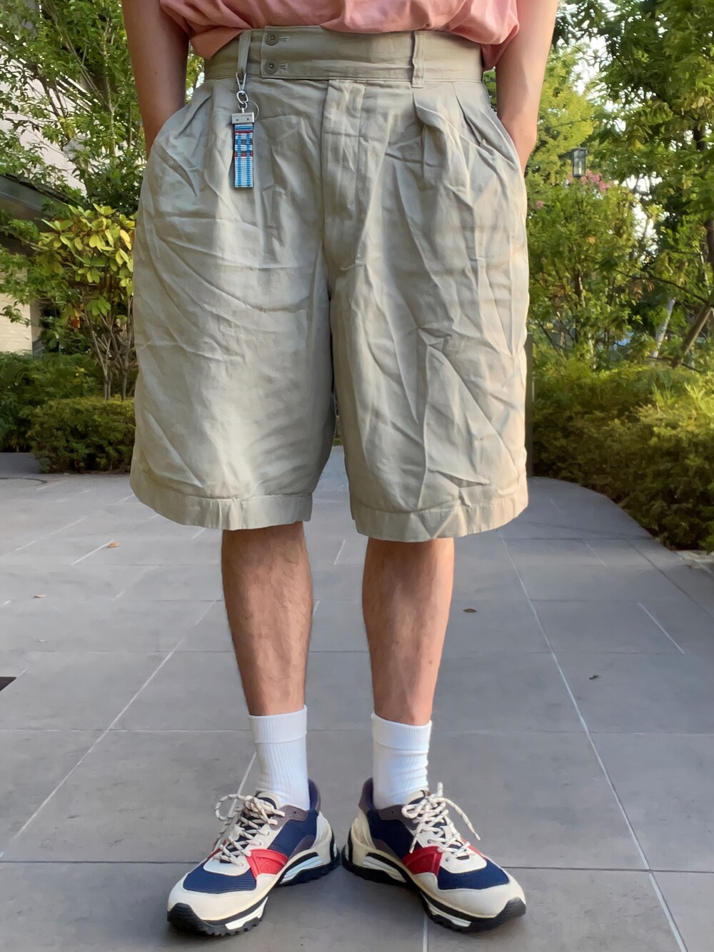 ピンク系のTシャツ/カットソー、ベージュ系のパンツ、ホワイト系のスニーカーを着用したメンズの夏コーディネートの4枚目の写真