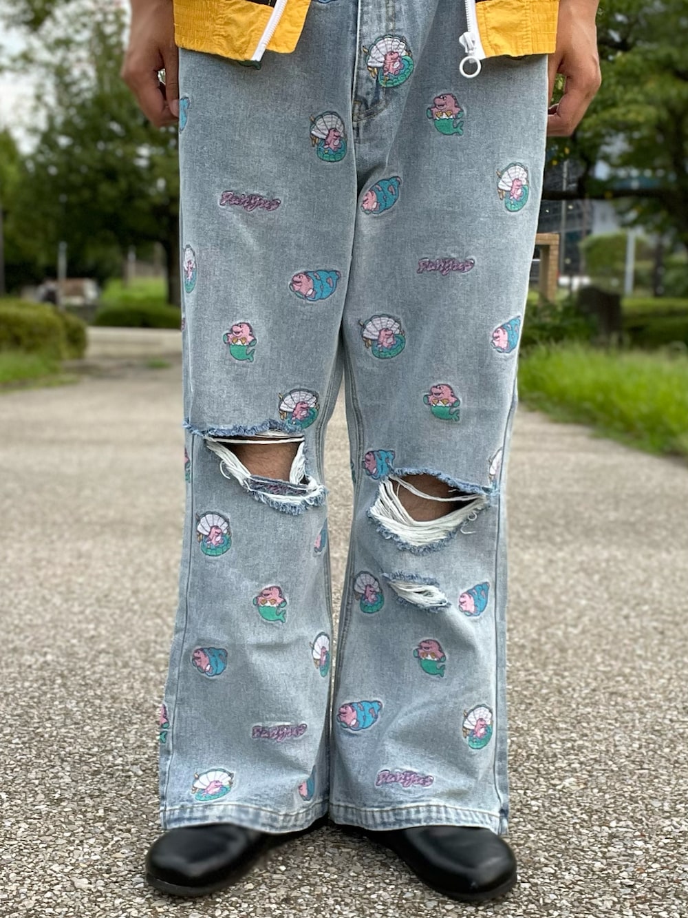 イエロー系のナイロンジャケット、ピンク系のTシャツ/カットソー、ブルー系のデニムパンツを着用したメンズの秋コーディネートの3枚目の写真