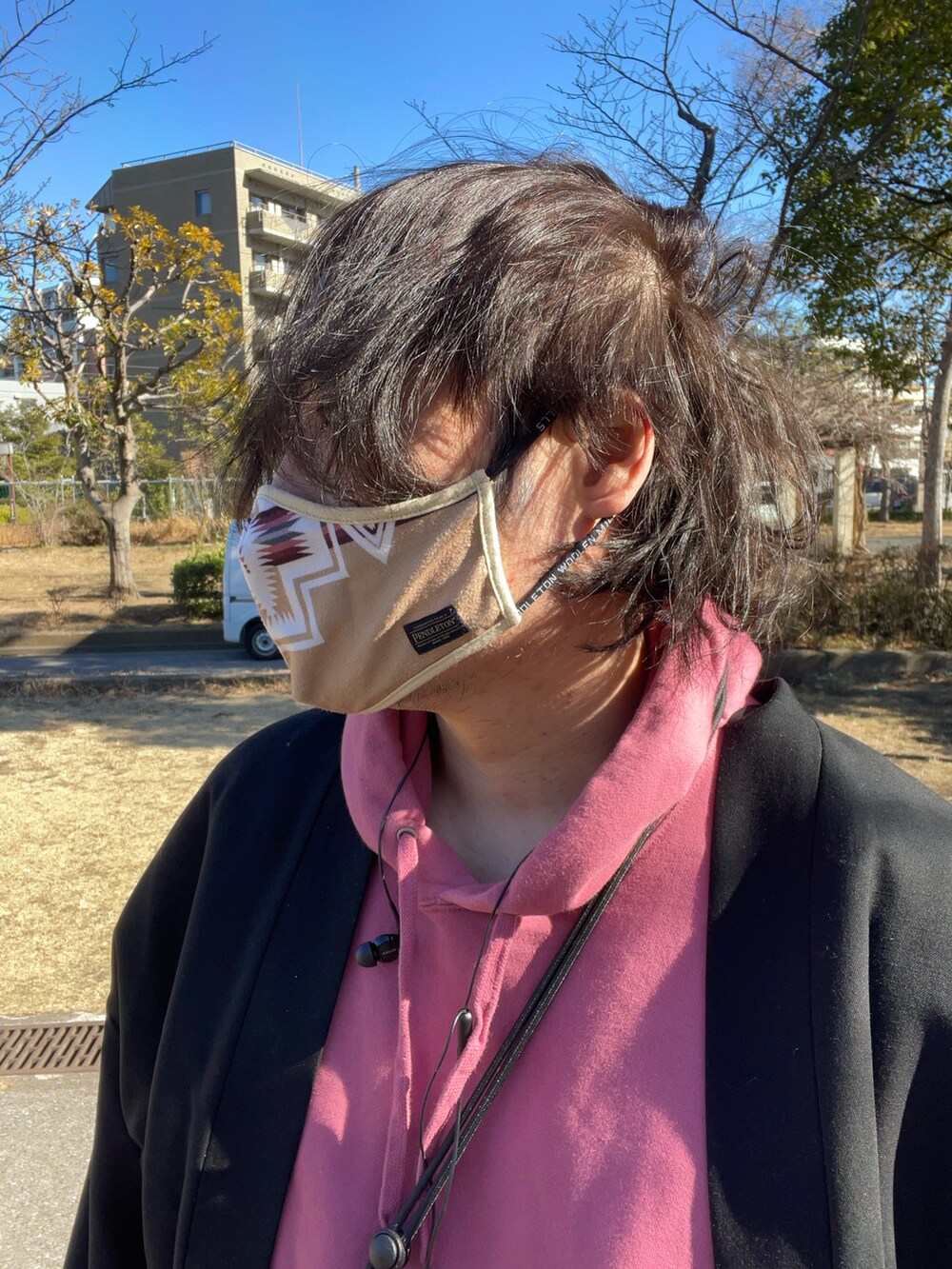 ブラック系のノーカラージャケット、ピンク系のパーカー、グレー系のパンツを着用したメンズの冬コーディネートの3枚目の写真