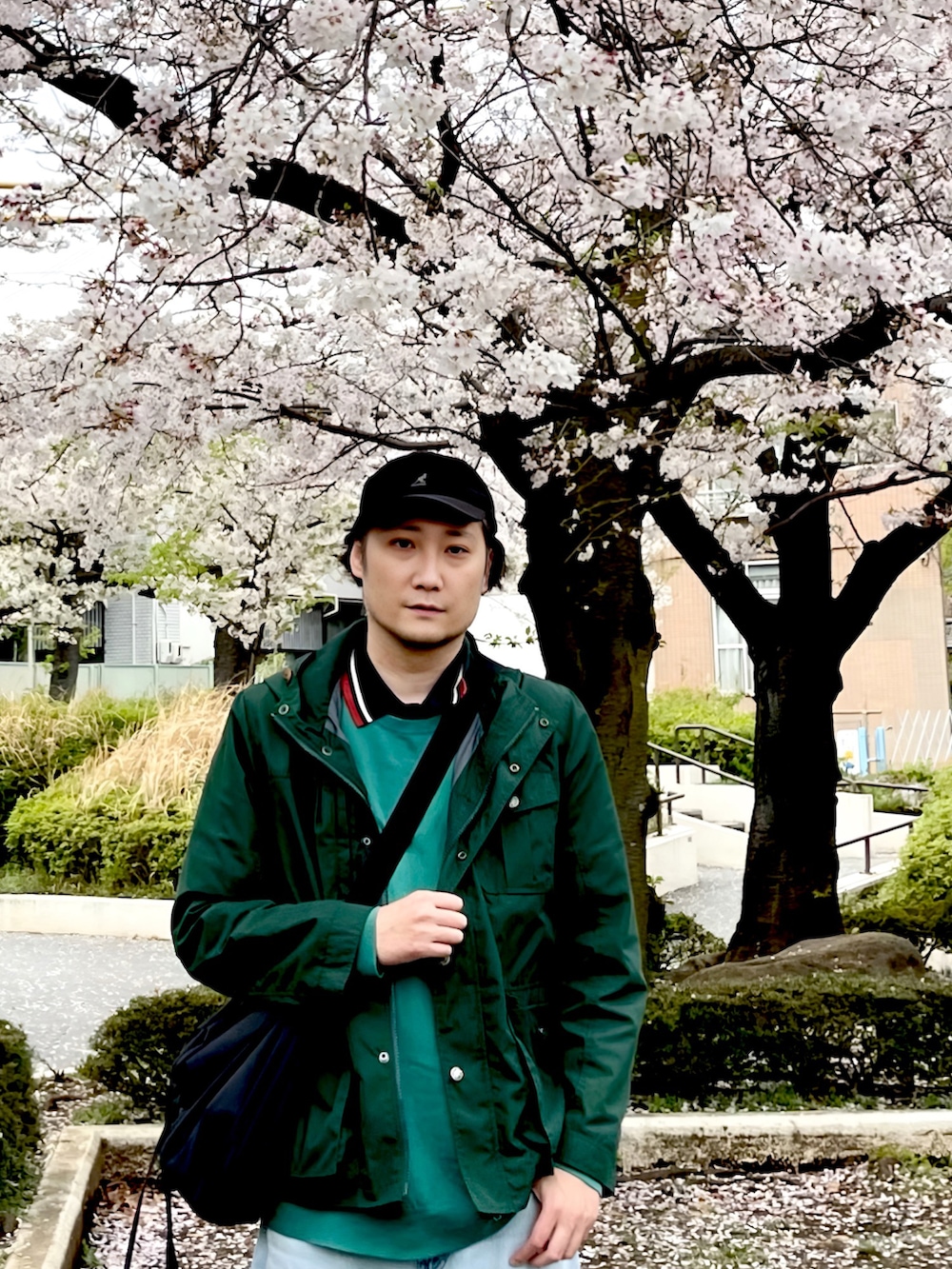 グリーン系のマウンテンパーカー、グリーン系のニット/セーター、ブラック系のショルダーバッグを着用したメンズの春コーディネートの3枚目の写真