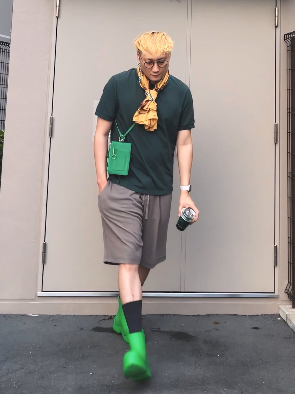 グリーン系のポロシャツ、グリーン系のレインシューズ、グリーン系のショルダーバッグを着用したメンズの夏コーディネートの4枚目の写真