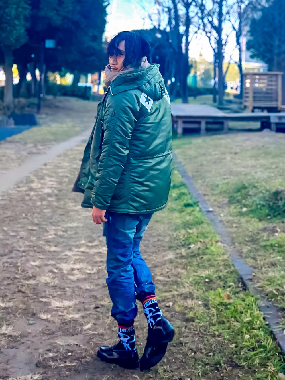 グリーン系のミリタリージャケット、ブルー系のデニムパンツ、ブラウン系のローファーを着用したメンズの冬コーディネートの2枚目の写真