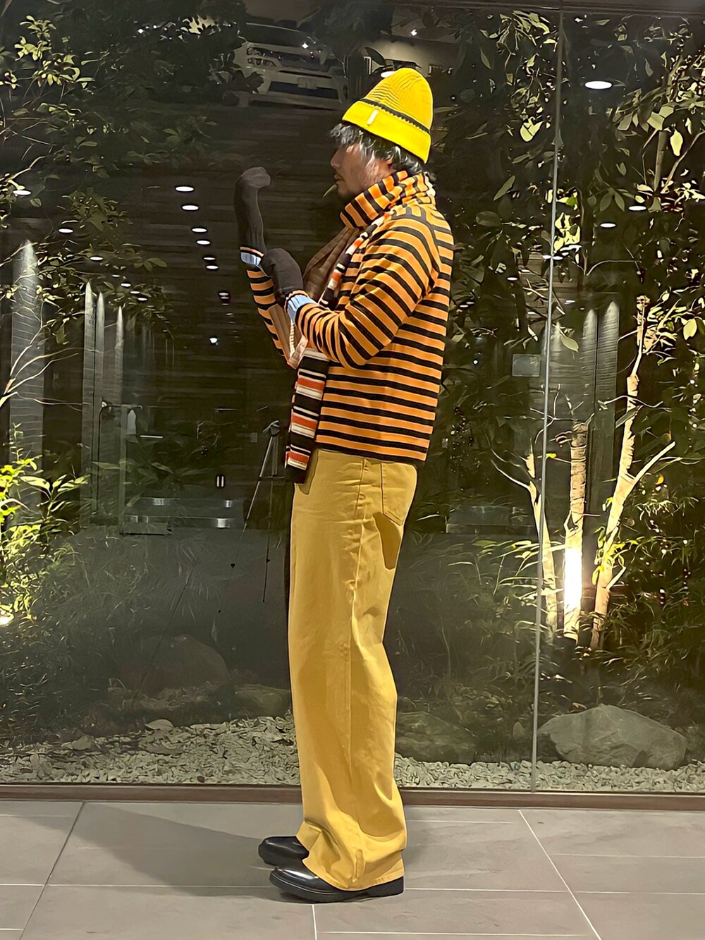 グレー系のTシャツ/カットソー、オレンジ系のニット/セーター、イエロー系のパンツを着用したメンズの冬コーディネートの2枚目の写真