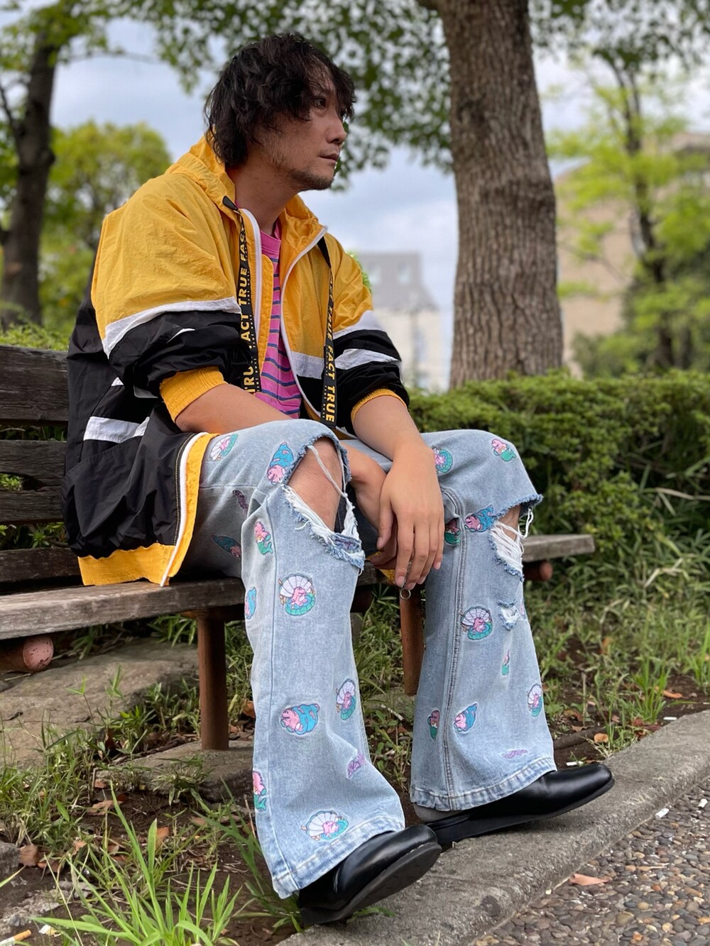 イエロー系のナイロンジャケット、ピンク系のTシャツ/カットソー、ブルー系のデニムパンツを着用したメンズの秋コーディネートの4枚目の写真