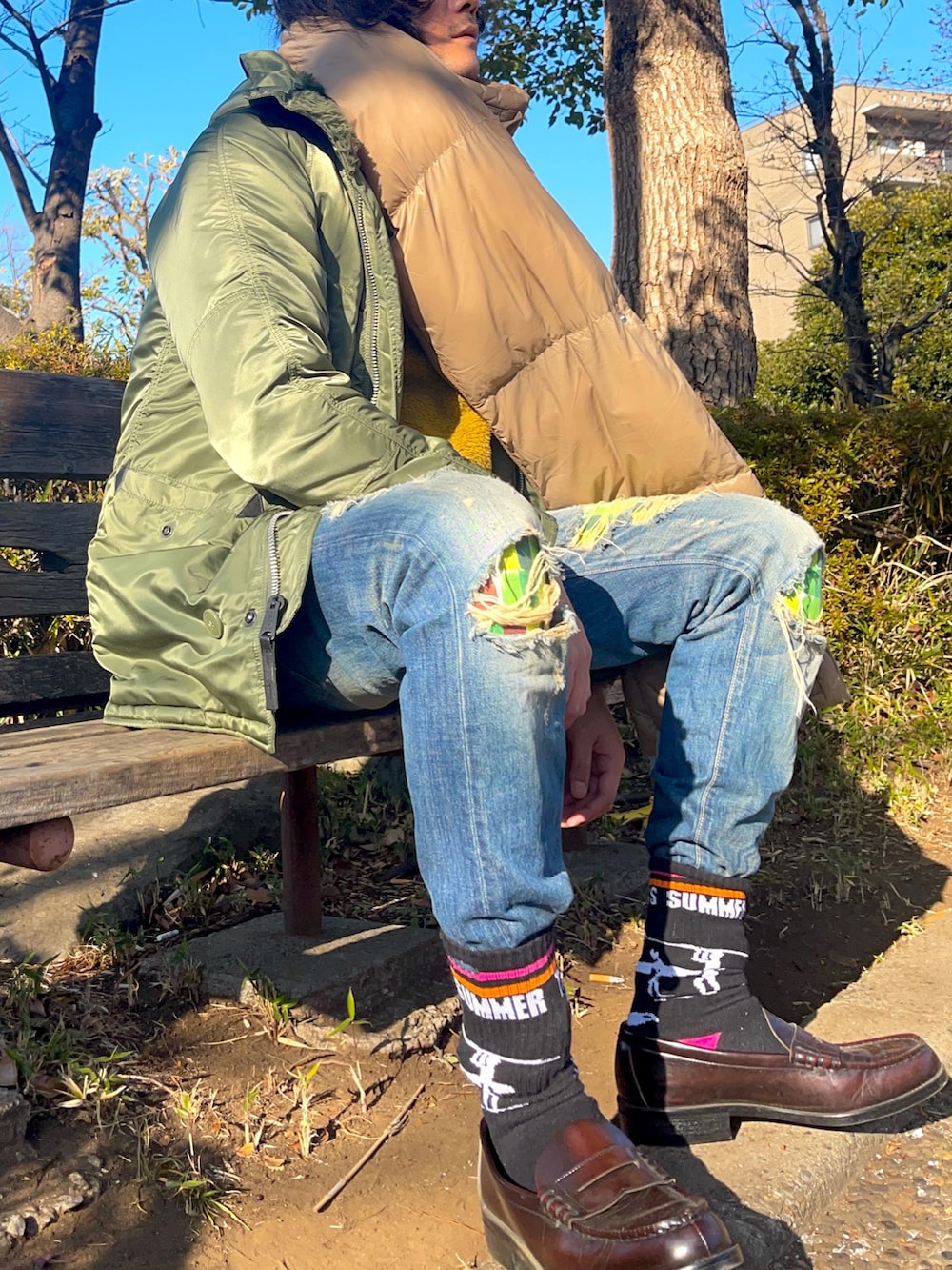 グリーン系のミリタリージャケット、ブルー系のデニムパンツ、ブラウン系のローファーを着用したメンズの冬コーディネートの4枚目の写真