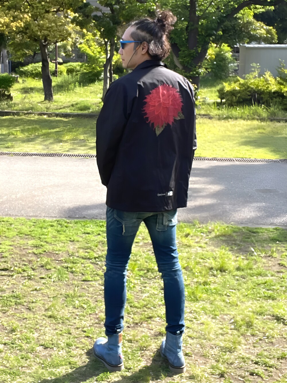 ブラック系のナイロンジャケット、ブルー系のTシャツ/カットソー、ブルー系のデニムパンツを着用したメンズの春コーディネートの4枚目の写真