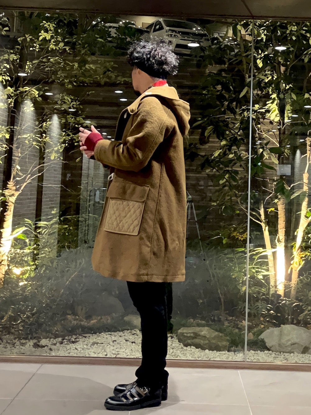 グリーン系のダッフルコート、ブラック系のニット/セーター、ブラック系のパンツを着用したメンズの冬コーディネートの2枚目の写真