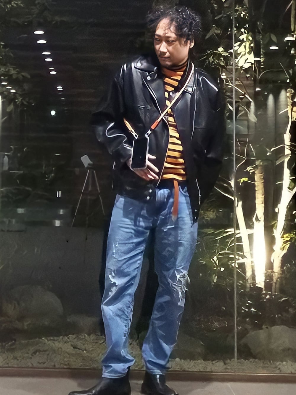 ブラック系のライダースジャケット、ブルー系のデニムパンツ、オレンジ系のニット/セーターを着用したメンズの冬コーディネートの3枚目の写真