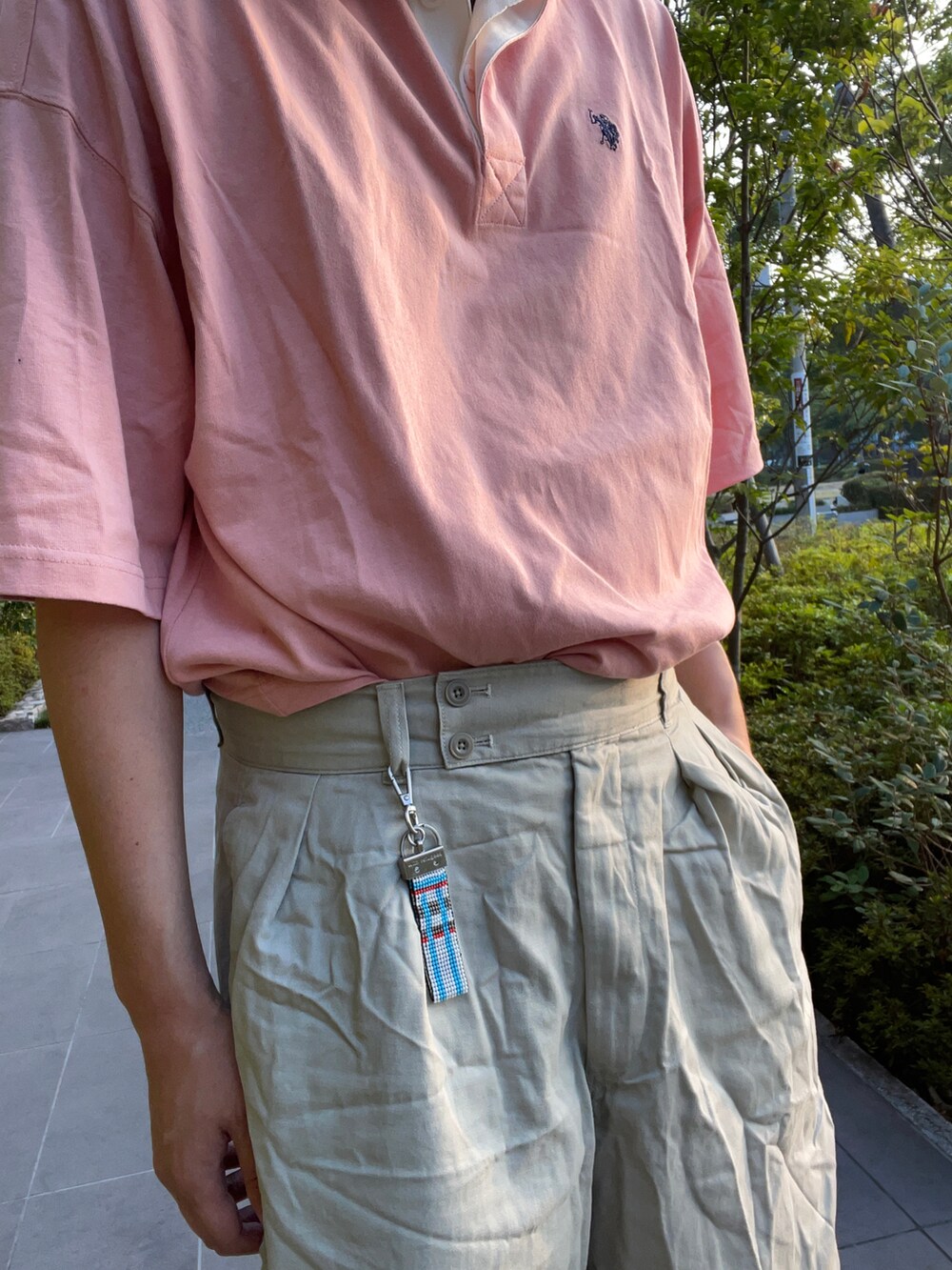 ピンク系のTシャツ/カットソー、ベージュ系のパンツ、ホワイト系のスニーカーを着用したメンズの夏コーディネートの3枚目の写真