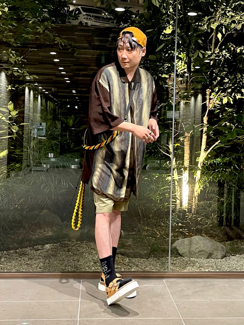 ブラウン系のシャツ/ブラウス、ベージュ系のパンツ、グリーン系のショルダーバッグを着用したメンズの夏コーディネートの2枚目の写真